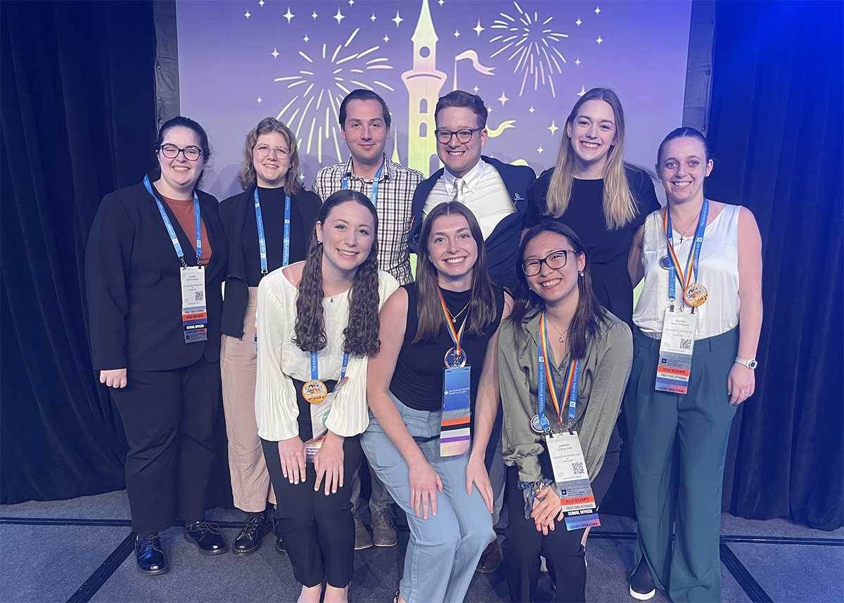 A group of student smile in front of a graphic of the Disney castle