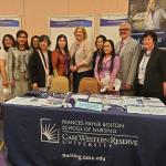 A group of faculty pose for photo in front of a table with FPB logo