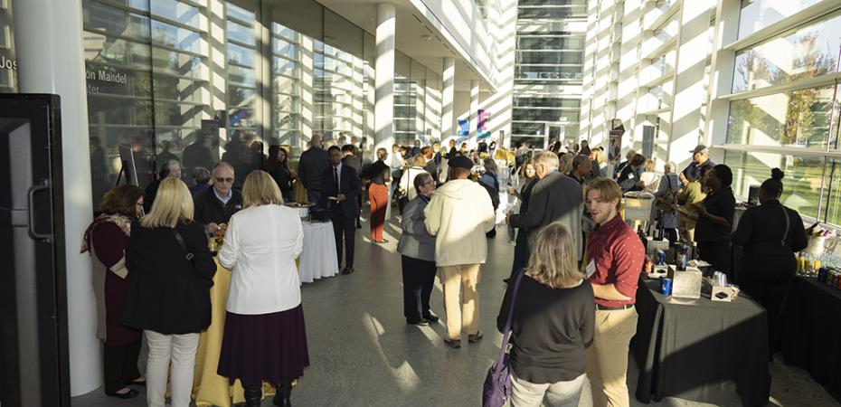 A group of people gather in a large windowed atrium to celebrate the 2023 FPB Alumni Awards