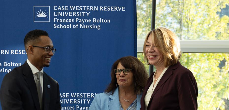 Three people in professional attire smiling in front of a blue backdrop for the Case Western Reserve University Frances Payne Bolton School of Nursing.