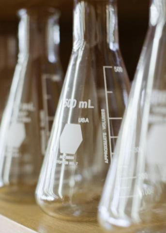Photo of three lab beakers lined up on a shelf. 