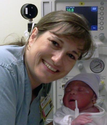 Leslie Ann Stroud, certified nurse midwife, smiling with a newborn baby.