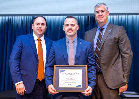 Tom Baum, center, holding his Innovator of the Year Award, with men on either side of him