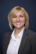Portrait of a smiling woman with short blonde hair wearing a white blouse and gray blazer