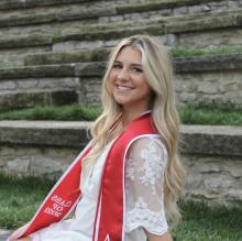 Woman with blonde hair wearing red graduation sash