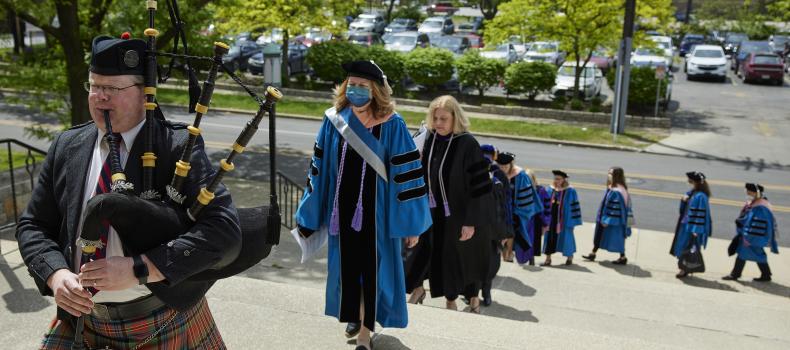 A bagpiper leads CWRU nursing faculty and students during graduation procession