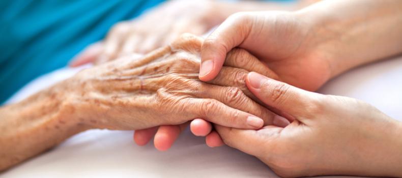 End of Life Care, elderly woman holding hands with younger person