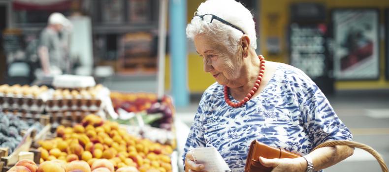 An older woman looks through produce at the grocery store