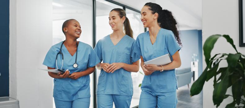 A trio of nurses, all women, walk and laugh together