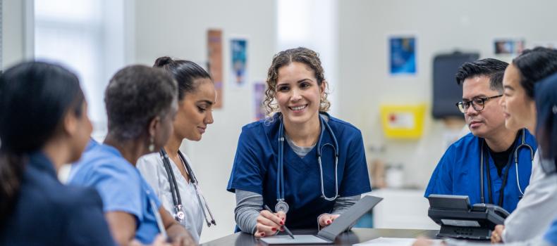 A group of nurses, centered around a single woman leading the discussion