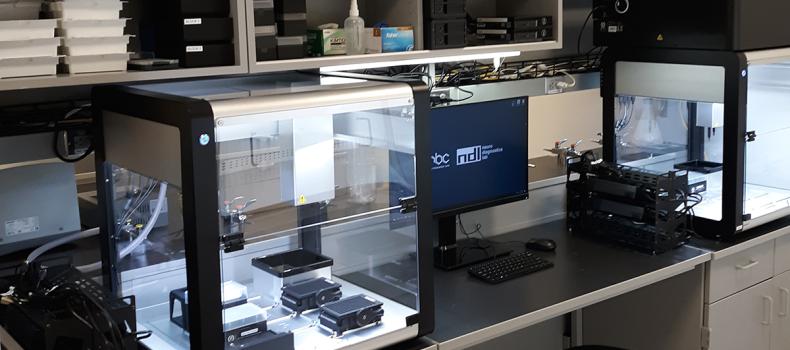 Inside the NRB lab, a desk with multiple technical devices, glowing white, and a computer monitor in the middle