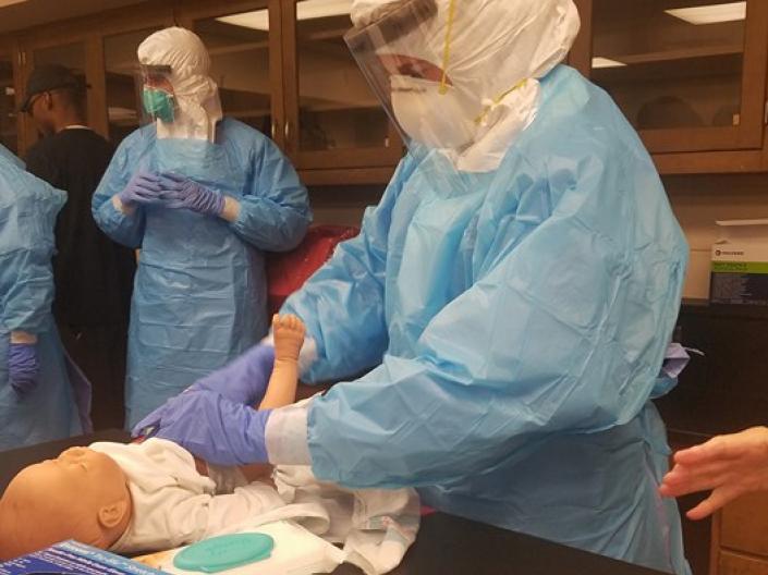 Caroline Hems donning PPE to practice taking care of a baby with Ebola in the nursing school.