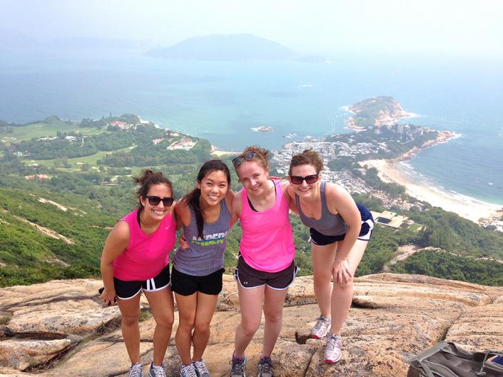 Students posing on the edge of a cliff in front of the ocean in Hong Kong.