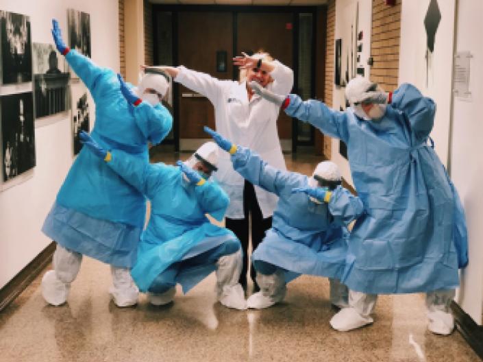 picture of students striking a pose in their scrubs with their instructor.