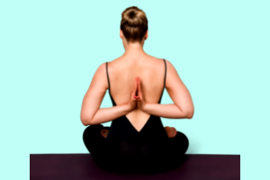 light blue background, woman sitting on ground on yoga mat facing backwards doing yoga pose