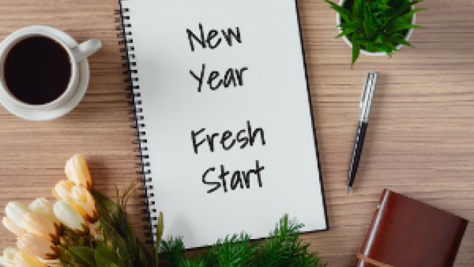 Planner on table with coffee and plants that says New Year Fresh Start