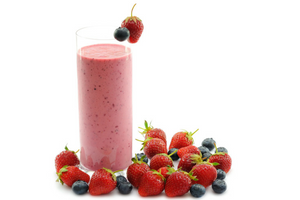 strawberry smoothie with strawberry and blueberry on rim of glass, surrounded by strawberries and blueberries