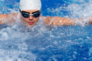 woman swimming in lap pool with white swim cap and goggles