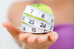 woman holding green apple with measuring tape around it in her hand