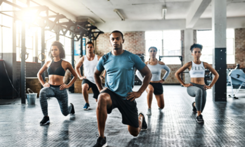 group of five people doing lunges in a small group setting in open gym
