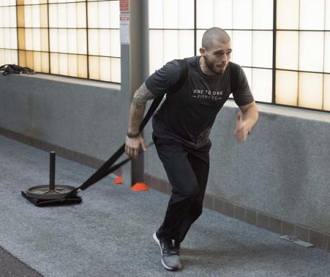 Man in t-shirt pulling a sled in a gyme