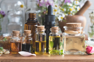 Various clear bottles with liquid on a table with flowers behind