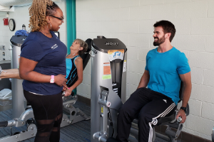 woman trainer with male on a leg extension machine