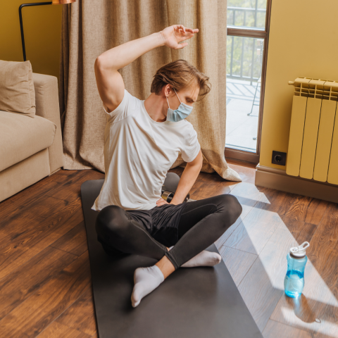Man on floor doing yoga wearing a mask