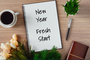 Planner on table with coffee and plants that says New Year Fresh Start