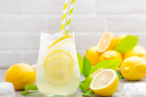 Glass pitcher with lemonade surrounded by lemons