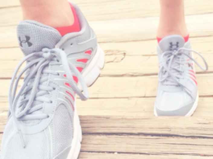 close up of woman's feet with grey underarmour running shoes walking up wooden stairs