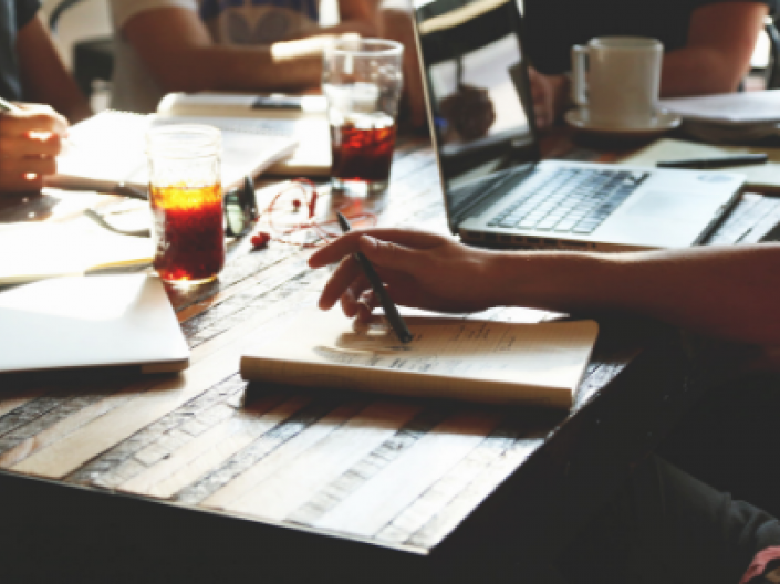 people sitting at table studying from notebooks and laptops with drinks