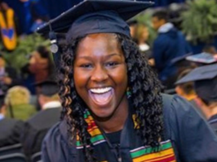 closeup of student smiling at graduation wearing black robes and cap
