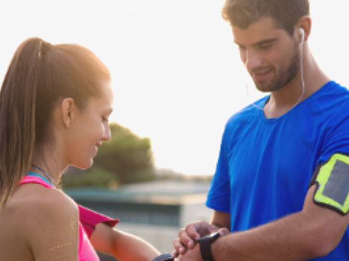 Man and women setting watches to exercise outdoors