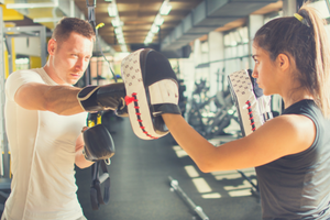 Man boxing hitting pads held by woman