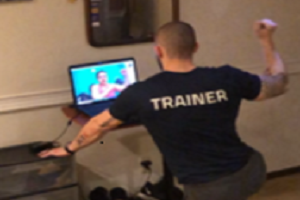 Man with trainer on the back of shirt looking at someone on computer screen