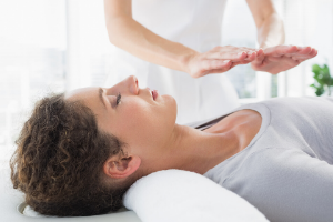 Woman experiencing Reiki with hands above chest