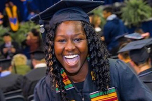 closeup of student smiling at graduation wearing black robes and cap