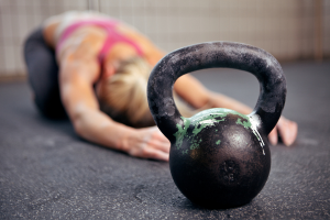 kettlebell in foreground, woman in downward dog yoga pose in background