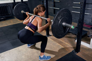 Women in squat position with barbell on shoulders