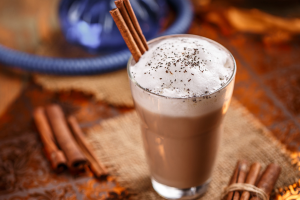 Photo of spiced chai drink with cinnamon sticks on table