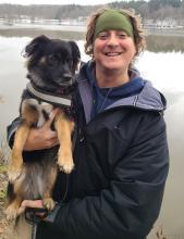 Photo of Postdoc Jeremy Didion with a dog by a lake