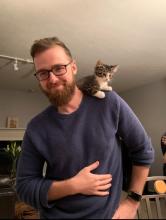Erik Price - Man with beard and glasses in blue sweater with kitten on shoulder