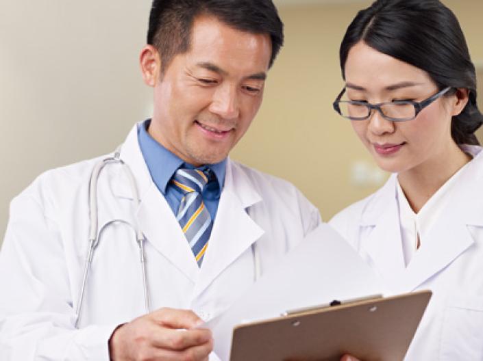 A doctor and his student reading a chart