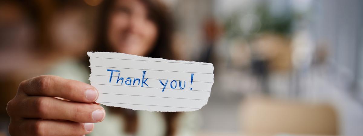 A person holding a slip of paper that says "Thank you"
