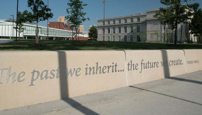 Concrete wall with lettering that says The past we inherit...the future we create. - Theo Moll