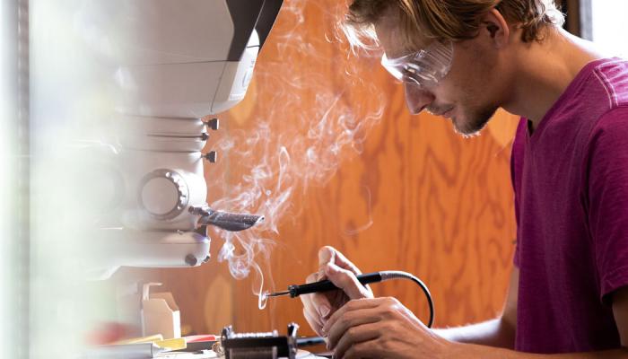 Side view of a person using a soldering tool