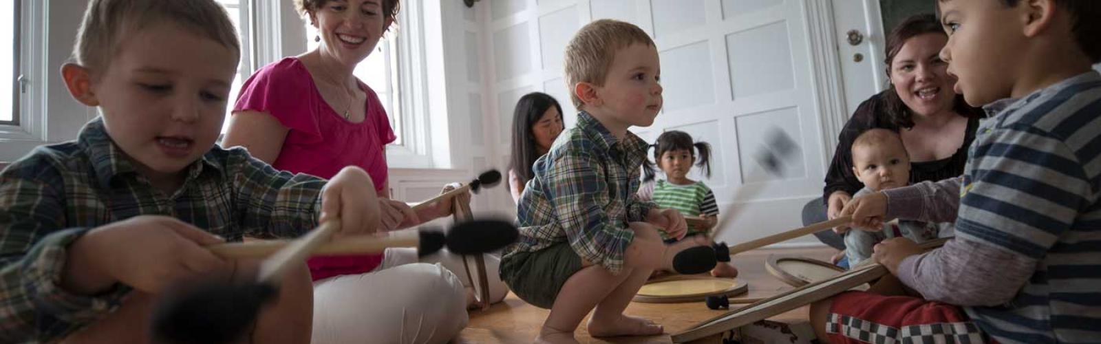 CWRU music faculty member sitting on the floor with young children playing instrument