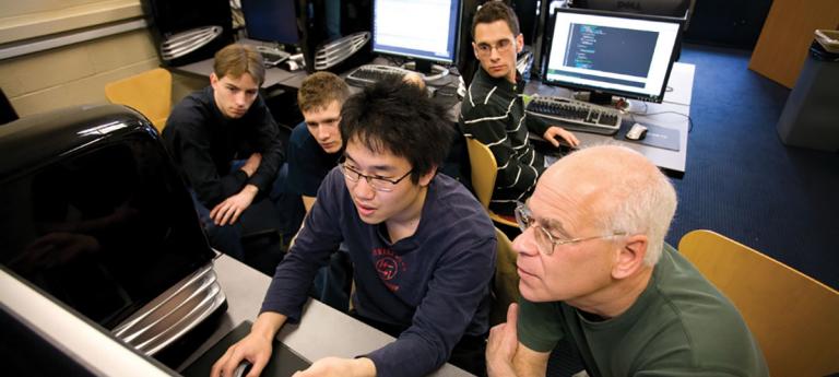 A faculty member looking at a computer with students
