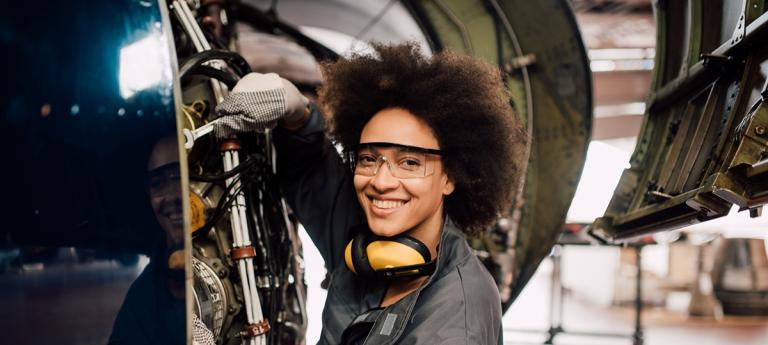 Happy young woman mechanic repairing airplane